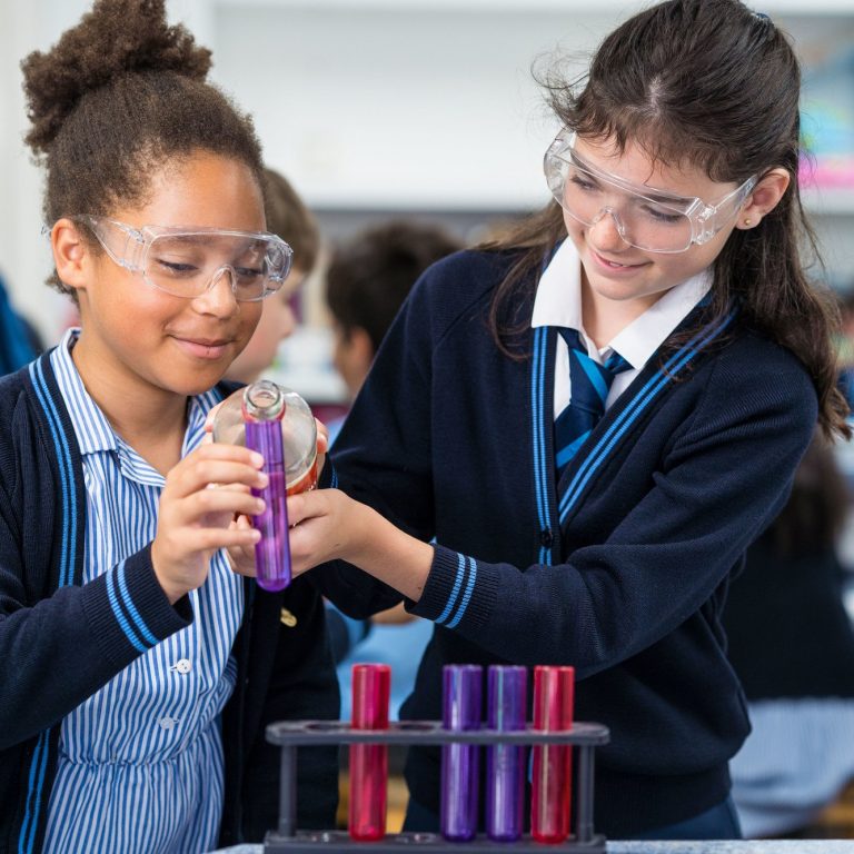 Students wearing goggles working with test tubes in the science class