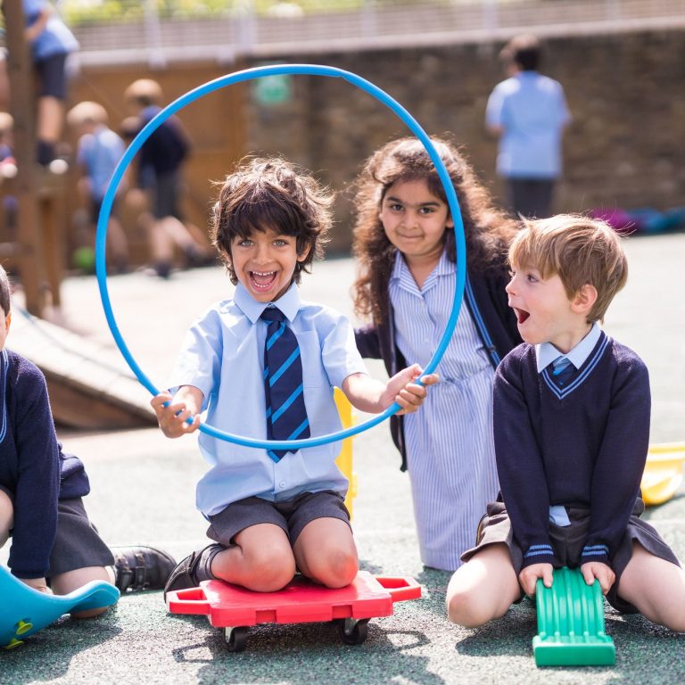 Student holding a hula hoop as others smile and look on