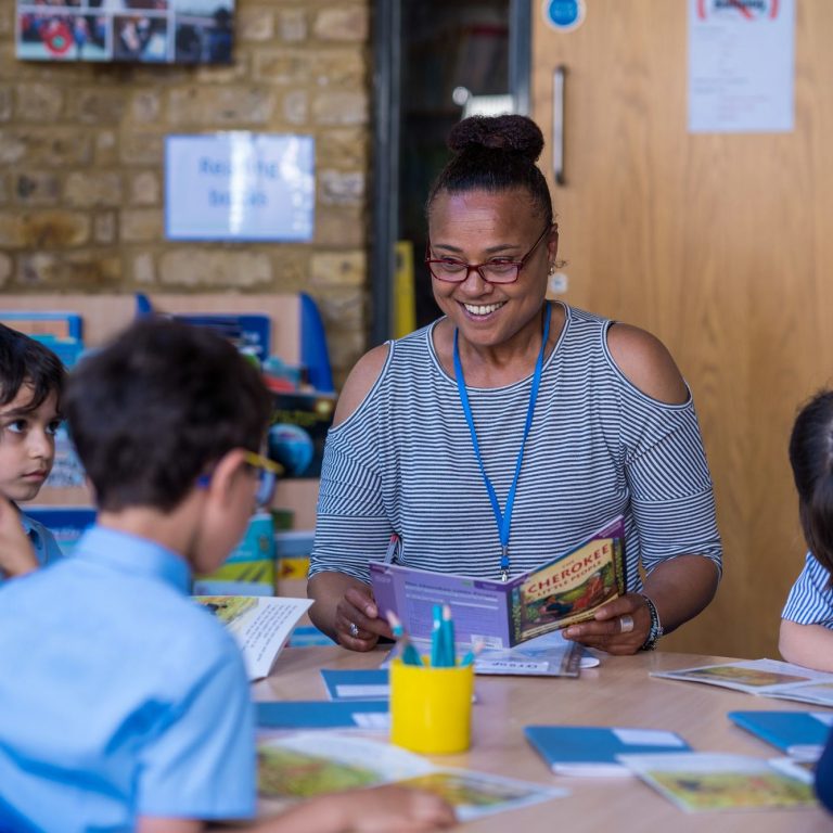 Students listening to the teacher as they read a book