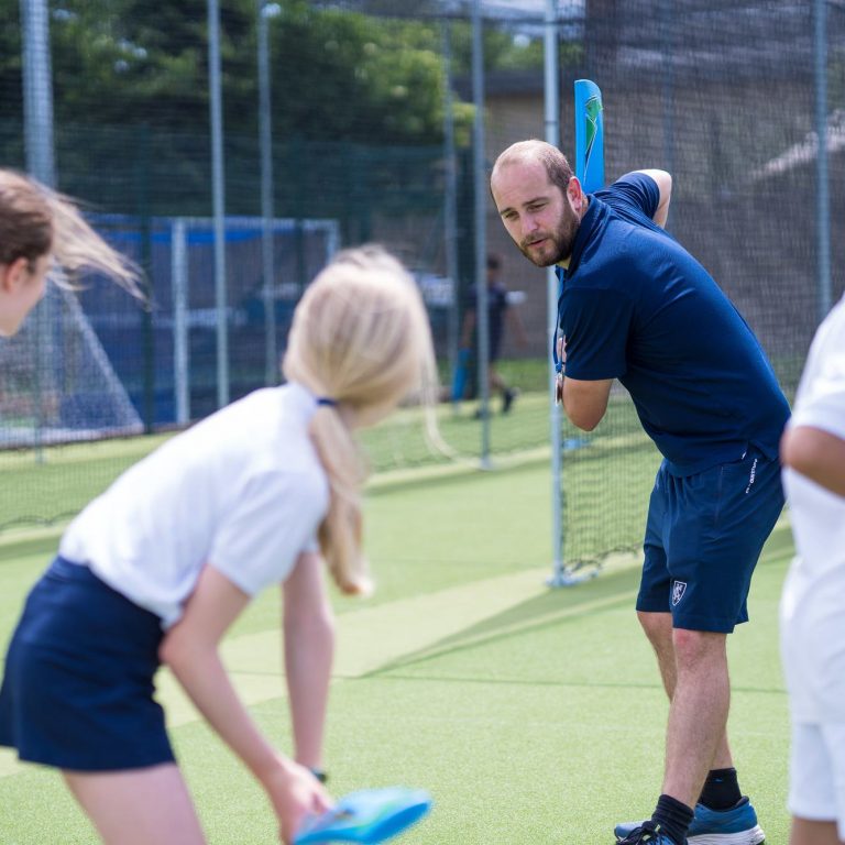 Teacher demonstrating how to hit a bat