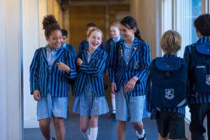 3 students in striped blue uniform walking down the corridor