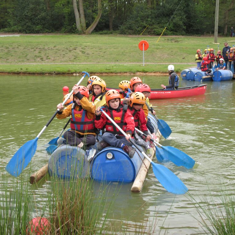 Children on a large kayak made with plastic barrels