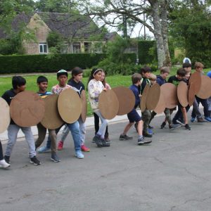 Students holding shields made with wood or cardboard