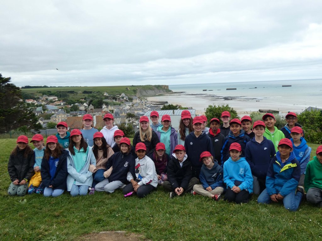 All students wearing red caps behind the beachfront