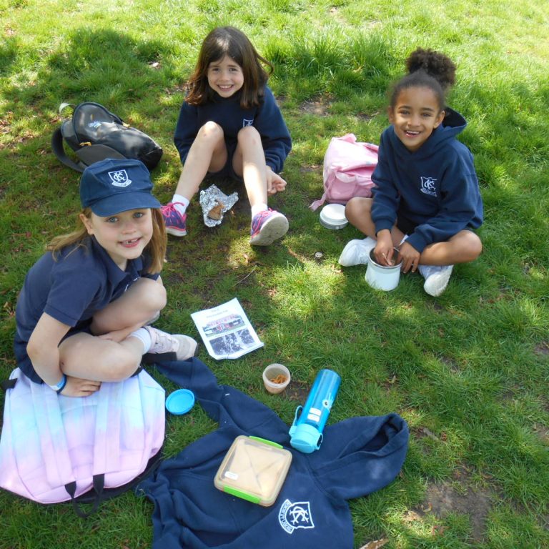 girls sat on grass, eating their lunch