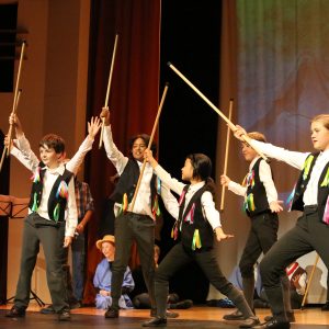 students holding sticks on stage